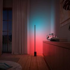 a pink and purple light shines on the wall next to a tall black pole