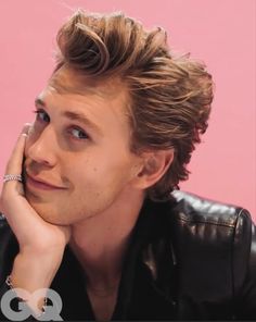 a close up of a person with a ring on his finger and a pink background