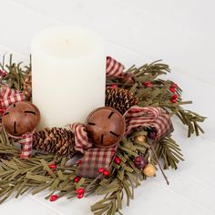 a white candle sitting on top of a wreath filled with pine cones and other decorations