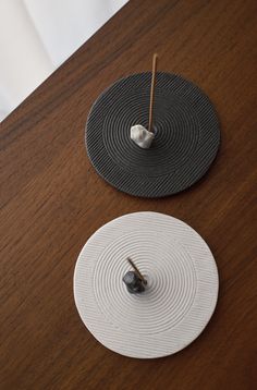 two coasters sitting on top of a wooden table next to a small candle holder