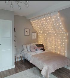 a bed room with a neatly made bed and some lights on the wall above it