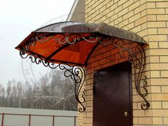 an umbrella is attached to the side of a building with a door and brick wall