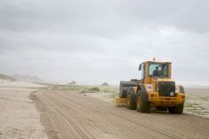 a tractor is driving down the dirt road