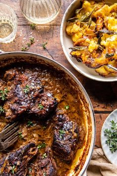 two bowls filled with meat and potatoes on top of a wooden table