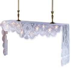 two candles are lit in front of a white table cloth with lacy lace on it