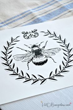 a black and white drawing of a bee on a piece of paper with leaves around it