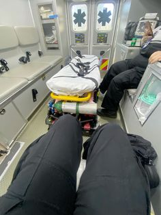 two people are sitting in an ambulance with their feet propped up on the floor and luggage