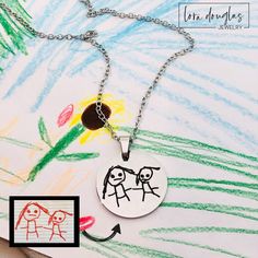 a child's drawing on a necklace with an image of two people holding hands