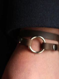 a close up of a person wearing a leather bracelet with a ring on it's side