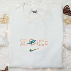 Nike x Miami Dolphins Logo Embroidered Hoodie, NFL Sports Embroidered Hoodie, Nike Inspired Embroidered Hoodie Welcome to Tinicloset, where every stitch tells a story and every garment is a testament to the enduring passion for sports and style. Nestled within our collection are treasures waiting to be discovered – custom embroidered shirts, sweatshirts, T-shirts, and hoodies that encapsulate the essence of athleticism and fashion. With an unwavering commitment to quality and innovation, we invi Nike Inspired, Miami Dolphins Logo, Dolphins Logo, Maroon Hoodie, Embroidered Shirts, Nike Sweatshirt, Nfl Sports, Hoodie Material, Nike Sweatshirts