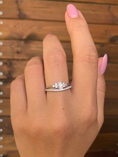 a woman's hand with pink manicured nails holding an engagement ring