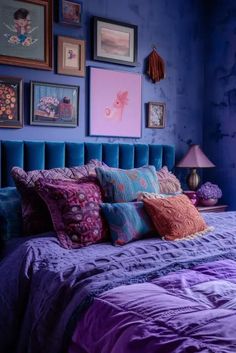 a bedroom with blue walls, purple bedding and pictures on the wall above it