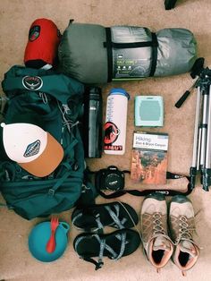 the contents of a backpack are laid out on the floor next to some camping gear