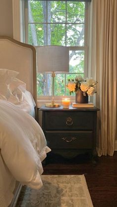 a bedroom with a bed, nightstand and window in the corner that has curtains on both sides