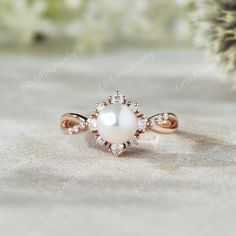 a pearl and diamond ring sitting on top of a table