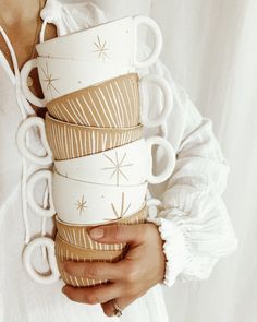 a woman holding stack of coffee cups in her hands