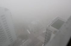 a foggy view from the top of a building in an area with tall buildings