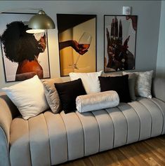 a living room with couches and pictures on the wall above them, along with hardwood flooring