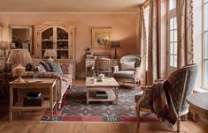 a living room filled with lots of furniture next to a large window and bookshelf