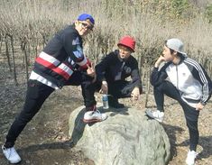 three young people standing on top of a rock