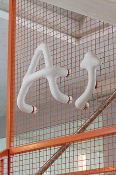 a white sign hanging from the side of a metal net in front of a building