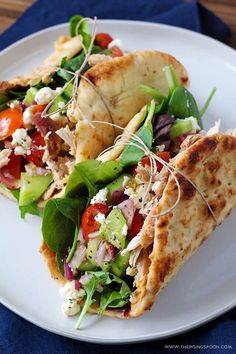 two pita sandwiches on a plate with lettuce, tomato and other toppings