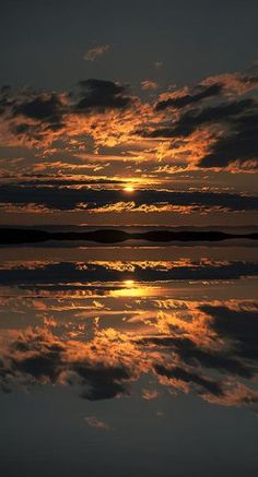 the sun is setting behind some clouds in the sky over water with reflections on it