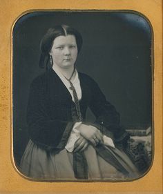 an old black and white photo of a woman wearing a long dress with her hands on her hips