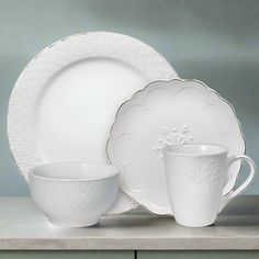 white dishes and cups sitting on top of a counter next to an empty cup with saucer