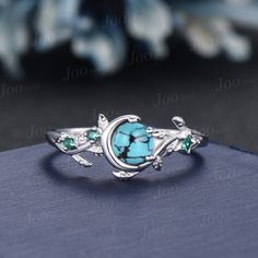 an image of a ring with turquoise stones and leaves on the front, sitting on top of a book