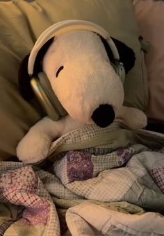 a stuffed dog with headphones on laying in bed