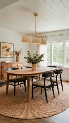 a dining room table with chairs and a rug on the floor in front of it