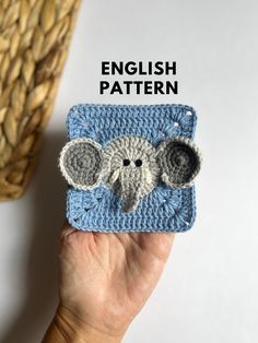 a hand holding up a small crocheted elephant in front of a basket with the words english pattern on it