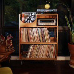 an old record player sits on top of a wooden shelf next to a potted plant