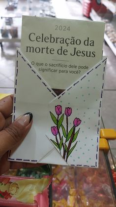 a person holding up a card with flowers on it and the words celebrago da morte de jesus written in spanish