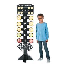 a young boy standing next to a sign with numbers and symbols on it that says race