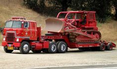 a red truck with a bulldozer attached to it's flatbed trailer