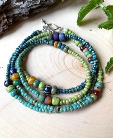 This Boho artistic beaded wrap bracelet or necklace is unique and colorful. Three shades of TINY seed beads in green, turquoise and blue are accented with decorative aged  Picasso beads.  This piece is 28 inches and wraps comfortably four times around wrists 6 to 6 1/2 inches. It can be adjusted longer or shorter depending on the size of the wrist. It is attached with a stylish diamond shaped pewter toggle clasp. It's easy to put on and take off but very secure.  This piece was inspired by a Pro Chocolate Designs, Chunky Turquoise Necklace, Wine Chocolate, Blue Turquoise Necklace, Turquoise Wrap Bracelet, Necklace Minimalist Jewelry, Hippie Bracelets, Multi Strand Bracelet, Jewelry Accessories Ideas