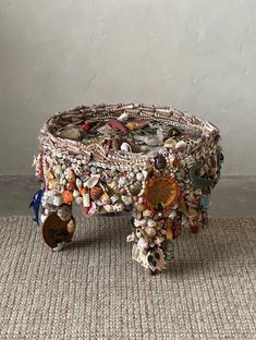 a table made out of shells and other items on the floor with a white wall in the background