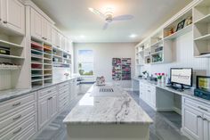 a large kitchen with white cabinets and marble counter tops, along with an island in the middle