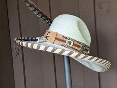 Kick up the Cowgirl in you with this amazing hat! This Gus style hat body is made of natural palm leaves. The brim is 4" and the crown is 5 1/2". The layered hat band starts with buttery soft deer skin and then overlaid with tan imprinted leather and Conchos. The back of the band is laced and has a deer antler bead. The brim has been laced with coordinating saddle leather lace. Finished with a long Venery Pheasant feather that complements all of the colors in this hat. All hats are made to order Natural Toquilla Straw Hat With High Crown, Adjustable High Crown Sun Hat For Vacation, Adjustable High Crown Toquilla Straw Panama Hat, High Crown Natural Panama Hat For Beach, High Crown Natural Color Panama Hat For Beach, Natural High Crown Panama Hat For Beach, Adjustable High Crown Straw Hat For Beach, Adjustable High Crown Straw Hat In Natural Color, Natural Color Hat With Short Brim For Western-themed Events