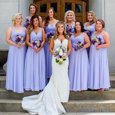 a bride and her bridal party pose for a photo outside the church door with their bouquets in hand