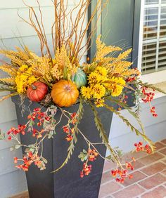 a planter filled with fall flowers and pumpkins