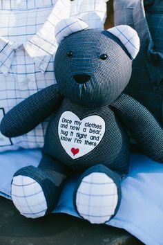 a black teddy bear sitting on top of a blue pillow with a heart shaped patch