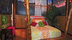 a bed in a bamboo room with lights on the ceiling and pictures hanging above it