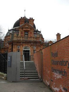 an old brick building with stairs leading up to the front door and gated entrance