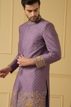 Purple sherwani with mandarin collar, all over checkered pattern zari work and floral pattern gold zardozi hand embroidered borders.
Components: 1
Pattern: Hand Embroidered
Type Of Work: Zardozi and Zari Work
Neckline: Mandarin Collar
Sleeve Type: Full Sleeves
Fabric: Dupion Silk
Color: Purple
Other Details: 
Embroidered collar
Front and side slits
Closure: Front concealed placket
Note: The pant worn by the model is not for sale
Occasion: Groom,Wedding - Aza Fashions Gold Chanderi Bandhgala With Traditional Drape, Gold Bandhgala In Chanderi With Traditional Drape, Ceremonial Sherwani With Zari Work In Chanderi, Gold Raw Silk Bandhgala With Cutdana Detailing, Gold Raw Silk Bandhgala With Cutdana, Traditional Drape Brocade Kurta With Dabka Work, Designer Raw Silk Sets With Intricate Embroidery, Designer Embroidered Brocade Sets, Eid Straight Kurta Bandhgala With Zari Work