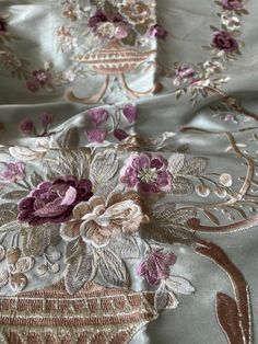 the fabric has flowers on it and is very elegantly embroidered in gold, purple, and silver