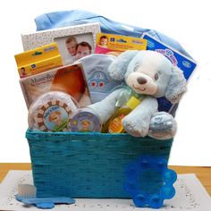 a teddy bear sitting in a blue basket filled with baby items