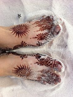 two feet covered in henna on the beach